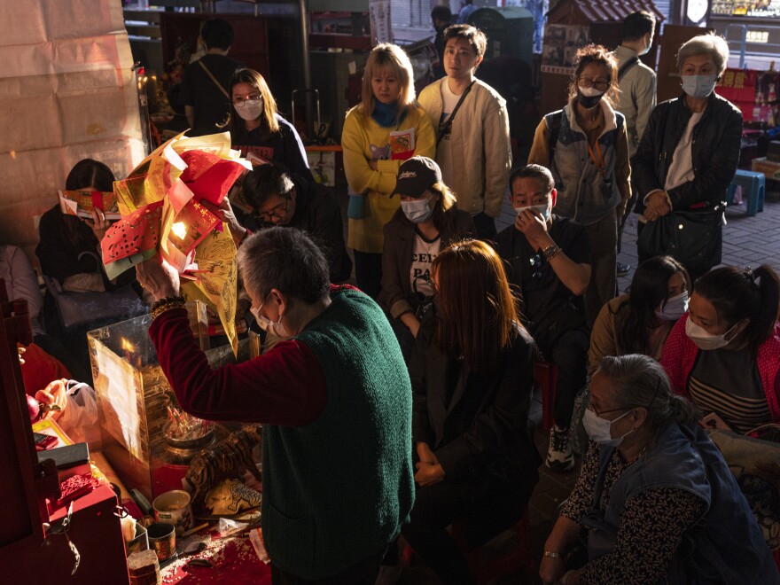 A practitioner performs a "villain hitting" ceremony as customers watch under the Canal Road Flyover in Hong Kong, on Sunday, March 5, 2023.