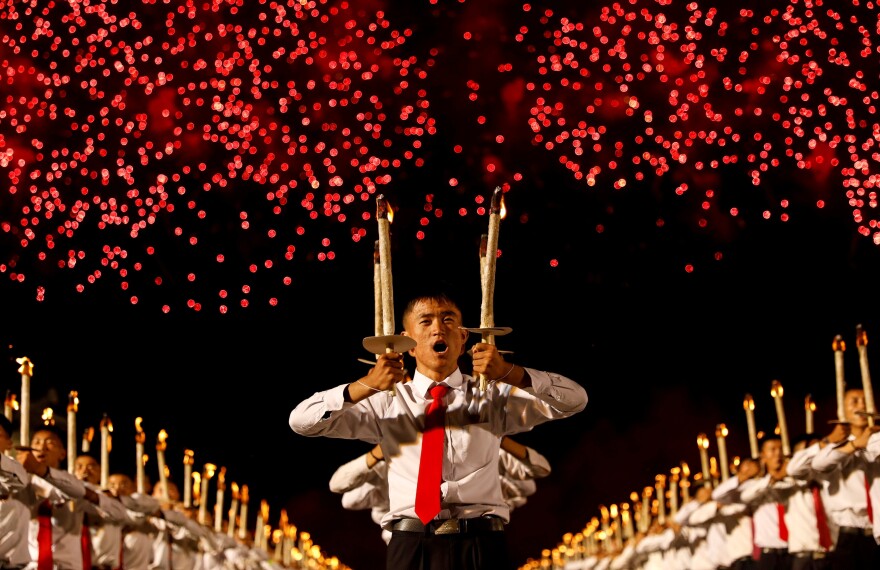 Fireworks explode over participants during a torchlight procession during the celebration marking the 70th anniversary of North Korea's foundation in Pyongyang, North Korea, on Sept. 10, 2018.