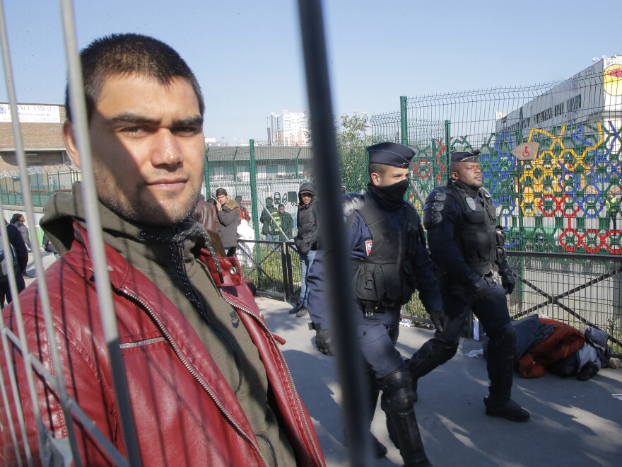 A young man looks on as police officers pace a makeshift camp they evacuated Tuesday.
