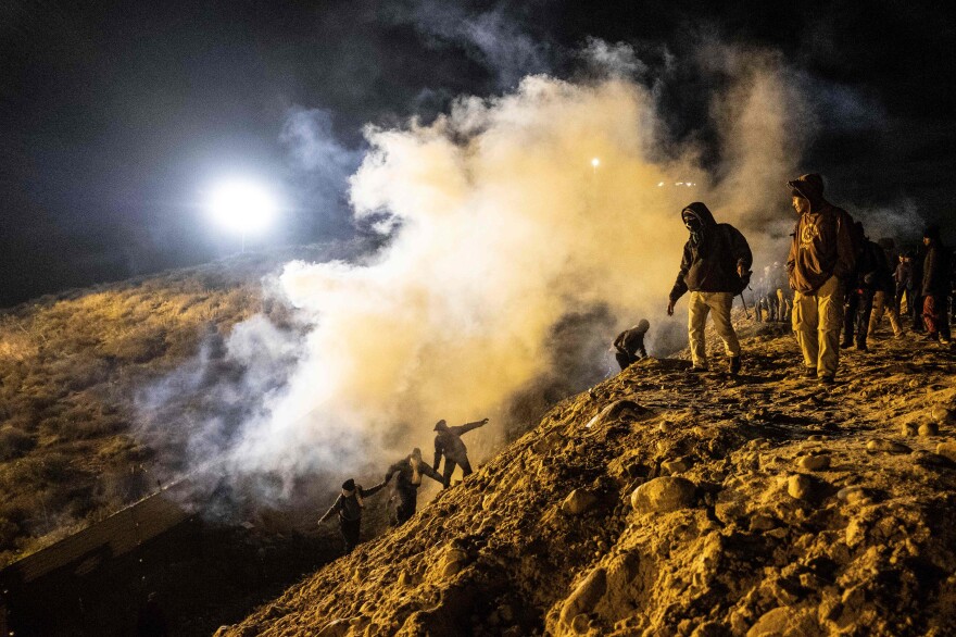 Central American migrants run away from tear gas thrown by the U.S. Border Patrol, after they tried to cross from Tijuana to San Diego on Jan. 1.