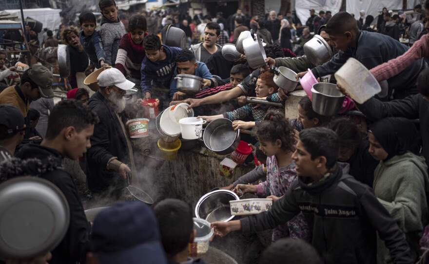 Palestinians line up for a free meal in Rafah, Gaza Strip.  International aid agencies say Gaza is suffering from shortages of food, medicine and other basic supplies as a result of the two and a half month war between Israel and Hamas. (Fatima Shbair/AP)