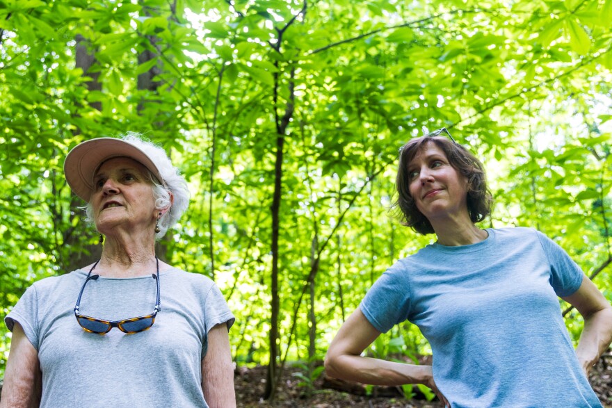 Two women are seen standing in front of trees