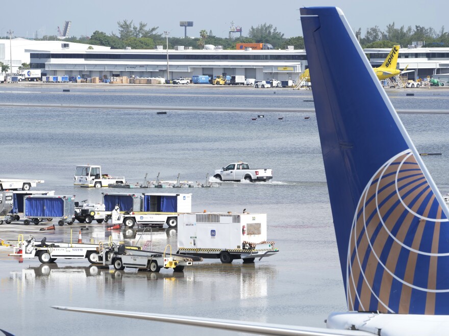 A truck drives on the flooded runway at Fort Lauderdale- Hollywood International Airport on Thursday. Nearly 26 inches of rain fell in a 24-hour period in the area, according to the National Weather Service.