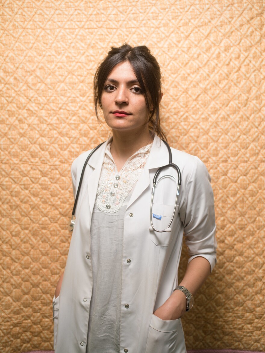 Hozan Badeea Sindi, now 27, stands in front of the blanket she slept under during her many months as an intern at a hospital in the Kurdish region of Iraq.