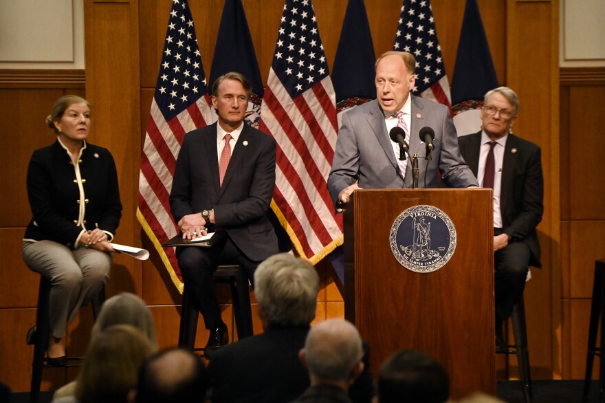 Four people are seen by a podium during a budget presentation.