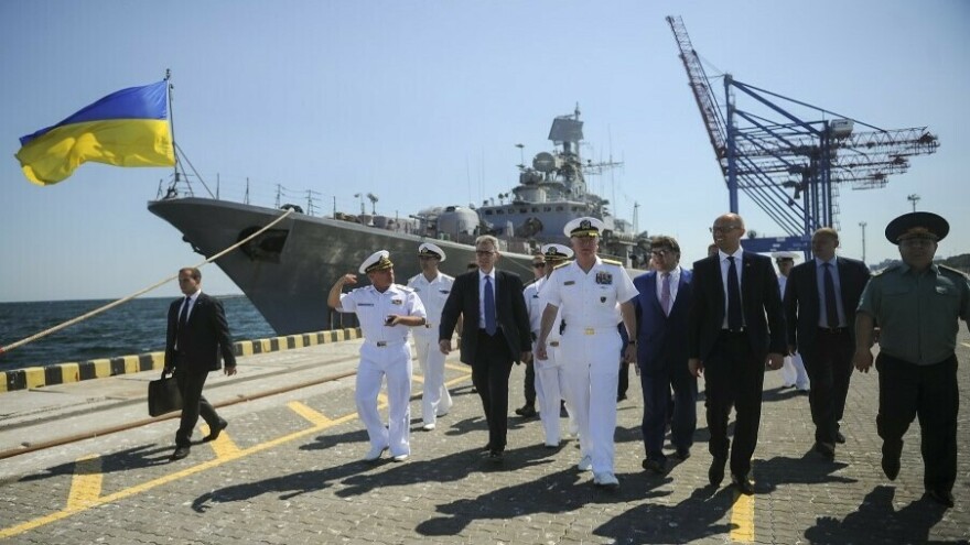 In this 2015 photo, U.S. Adm. James Foggo (center, in white uniform), meets Ukrainian leaders during training exercises between NATO and Ukraine in the port city of Odesa. The frigate in the background was the flagship of Ukraine's Black Sea fleet. But Ukraine chose to scuttle the warship, rather than risk it being captured by Russia when Moscow launched a full-scale invasion last year.