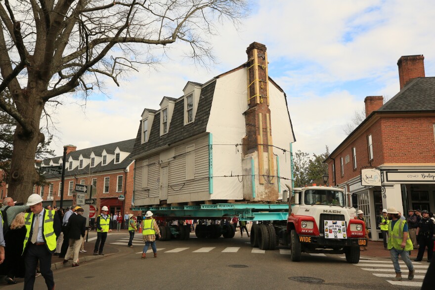 Truck moving house takes turn as construction workers monitor and crowd observes