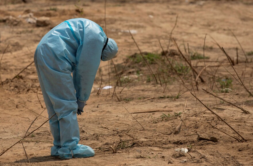 A health worker reacts on April 29, 2020, before the burial in New Delhi of a police officer who died of complications related to COVID-19.