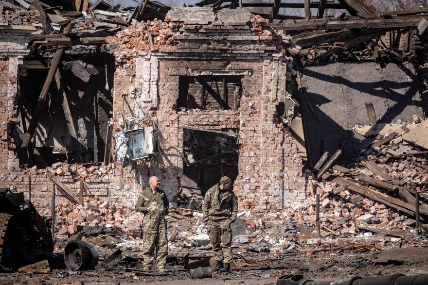 <strong>March 29:</strong> Ukrainian servicemen stand next to the rubble of a destroyed building in the northeastern Ukrainian city of Trostyanets.