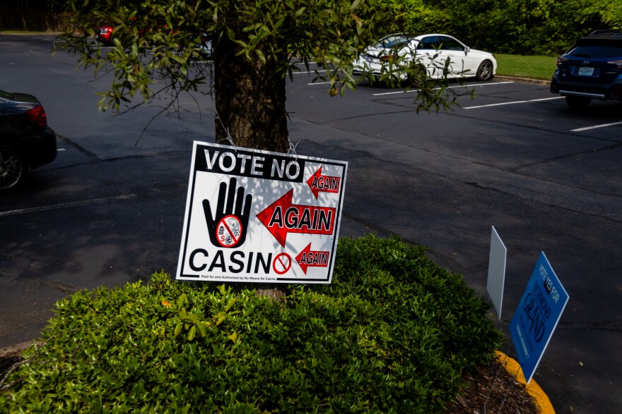 A sign for and against the casino are seen outside of the Office of Elections
