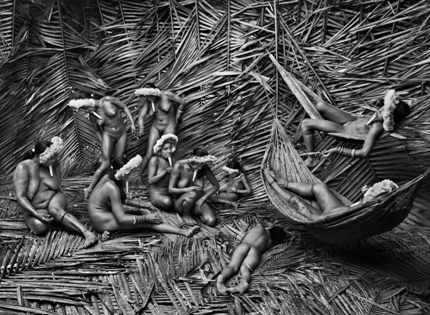 Women in Zo'é Indigenous Territory, State of Pará. Zo'é women generally use the red fruit of the urucum plant to color their bodies. They also use it in cooking. Urucum is a shrub native to the tropical zones of the Americas. Indigenous Americans have long used it for body painting, especially for painting the lips, hence its nickname: <em>árvore-batom</em> (lipstick tree).