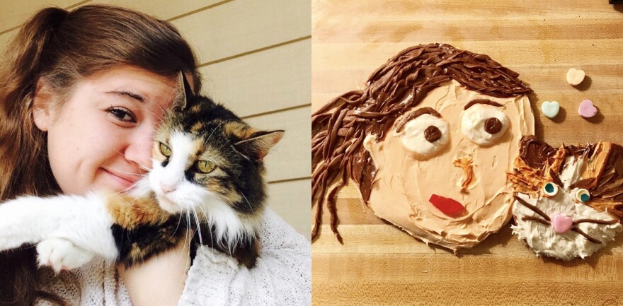 A photograph shows a close up of a young woman snuggling with her cat beside two cookies she made that portray what's in the photograph.