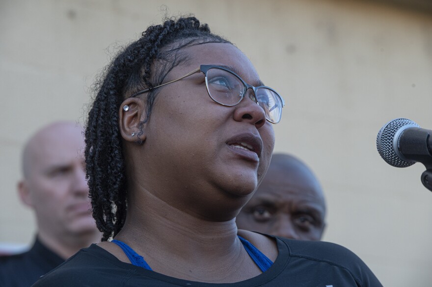 A person wearing glasses speaks into a microphone