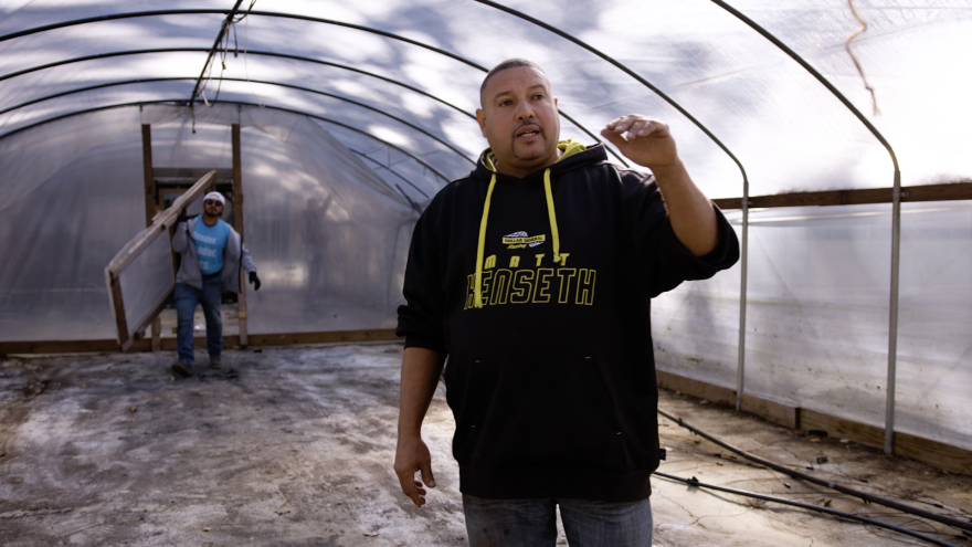A man standing inside of a hoop house as it is being built.