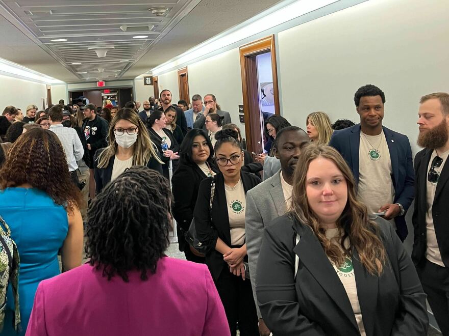 A group wearing shirts bearing a "We Belong Together" insignia lines up outside a Senate hearing room awaiting former Starbucks' CEO Howard Schultz's testimony on his handling of unionization efforts at Starbucks.