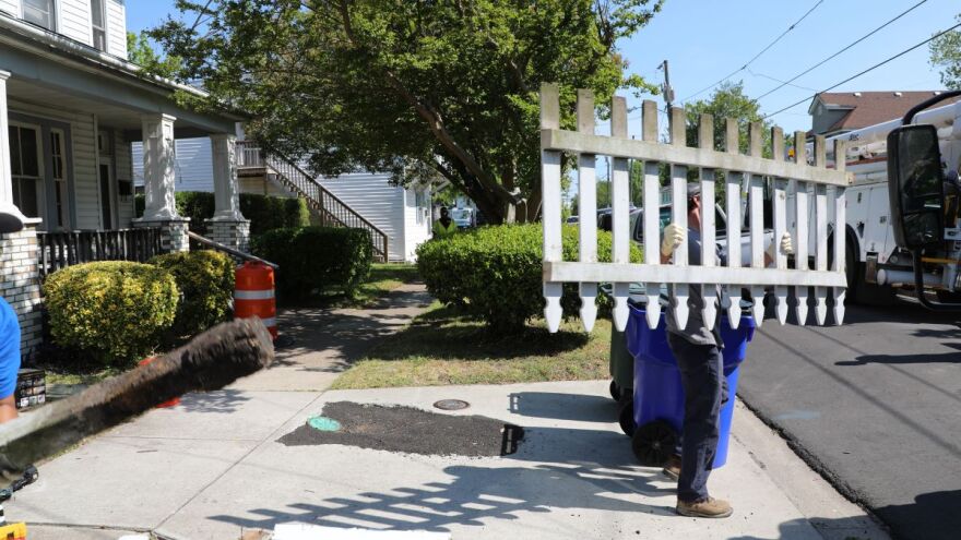 A person walks away from a home carrying a fence