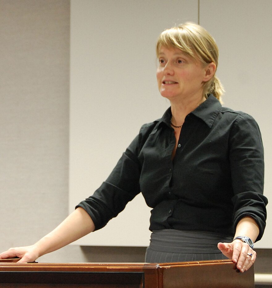 A person stands behind a podium and speaks
