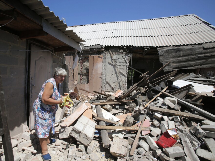 A woman walks in the ruins of a house after an artillery attack in the Ukrainian village of Mariinka on June 14. A conflict with Russian-backed separatists has killed 13,000 people since 2014.