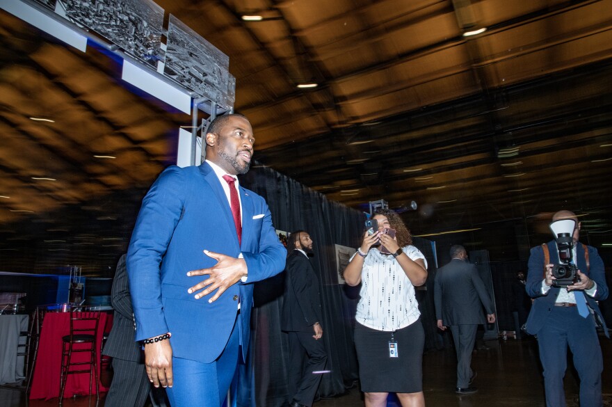 A person in a suit walks past photographers