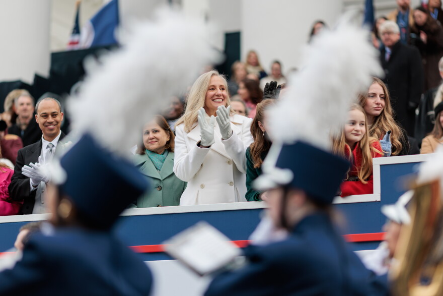 Jay Jones, Ghazala Hashmi, Abigail Spanberger and two of Spanberger's daughters are visible between the plumes of two marching band members' hats.