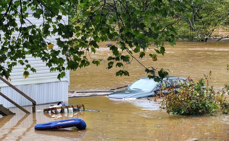 A car sits in floodwater up to its headlights.