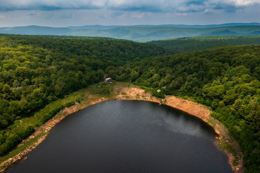 A cabin is seen on the bank of the lake