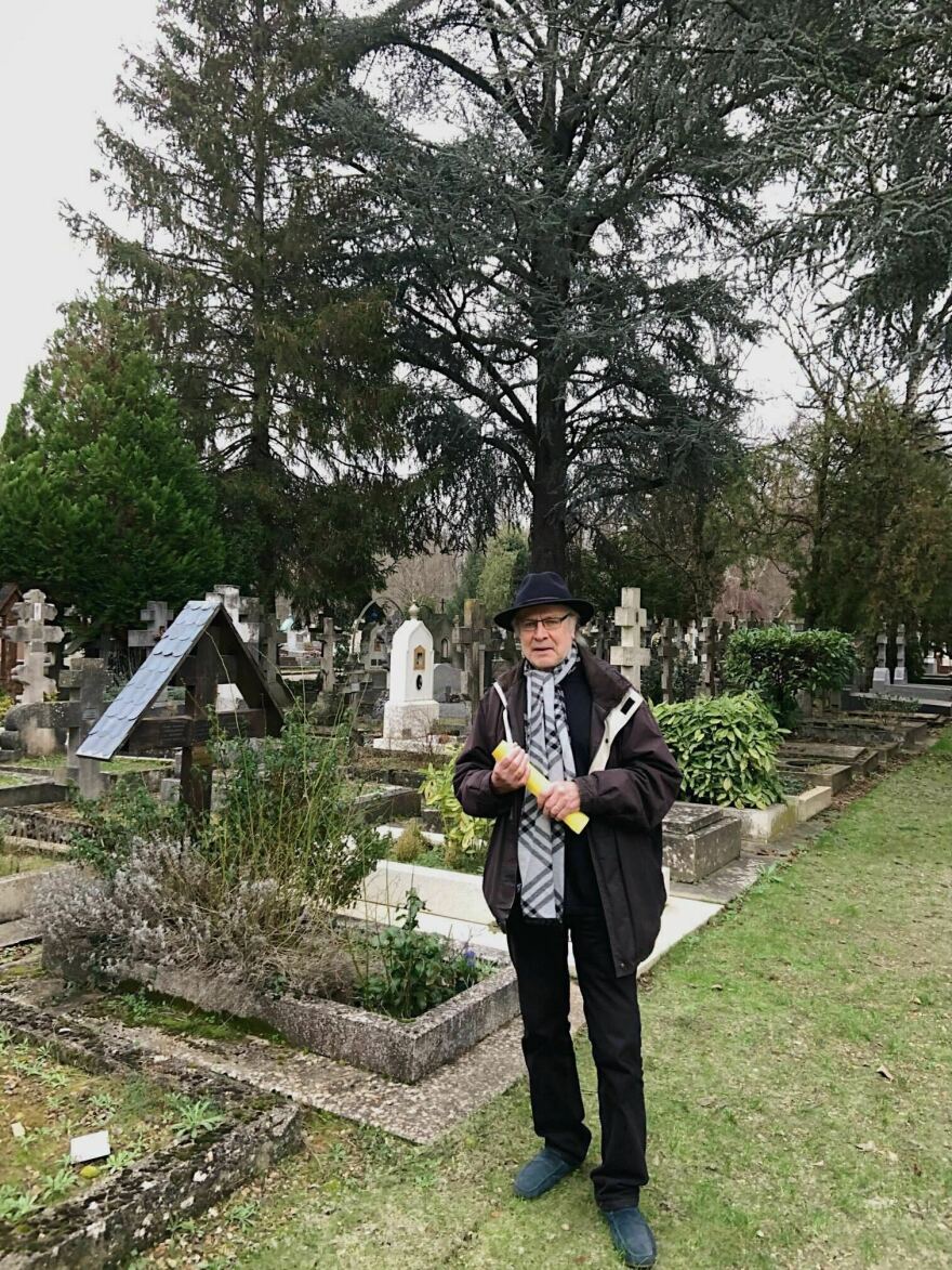 Christian Paillotin standing beside his mother's grave.