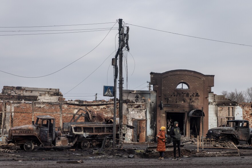 <strong>March 30:</strong> People stand amid destroyed Russian military vehicles close to the central train station that was used as a Russian base in Trostyanets.