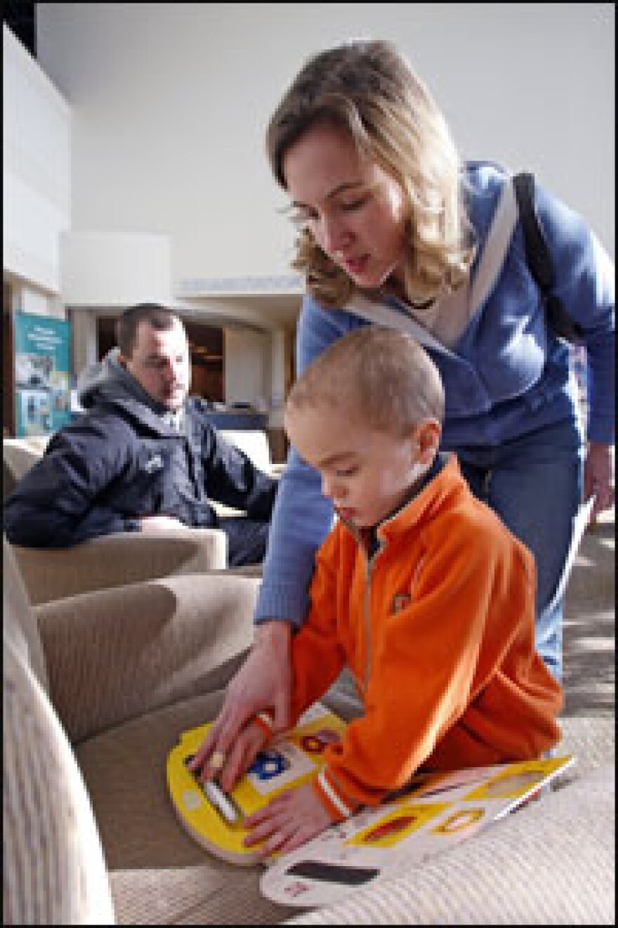 Katrina Brown says that watching her son Gibson learn is a bit like "watching grass grow." Her husband, Darrick, (back) watches her guide their son through a book.
